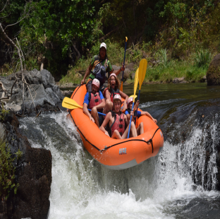 A group of people rafting down a river surrounded by lush vegetation.