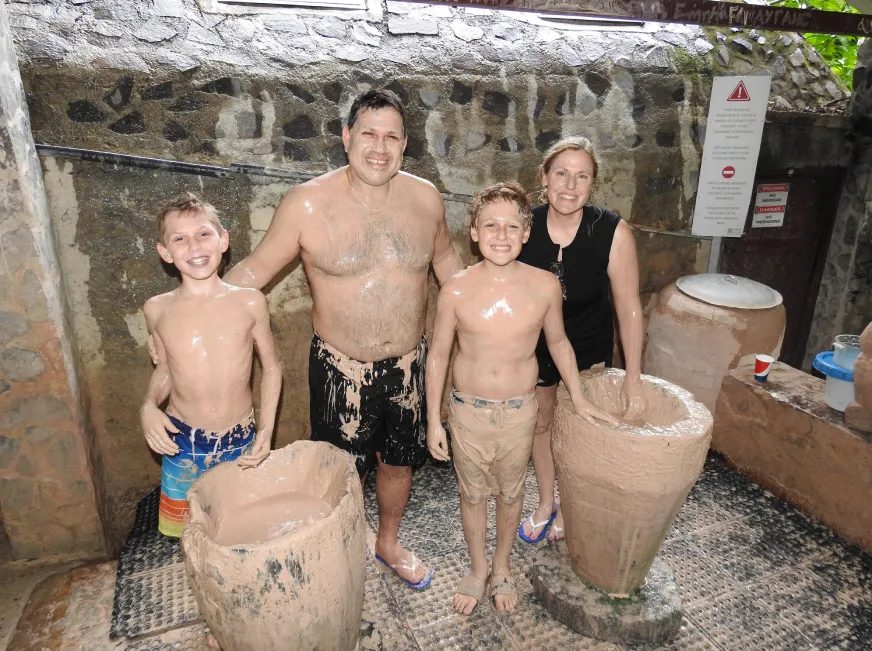 A family poses smiling next to large clay pots inside a rustic traditional workshop.