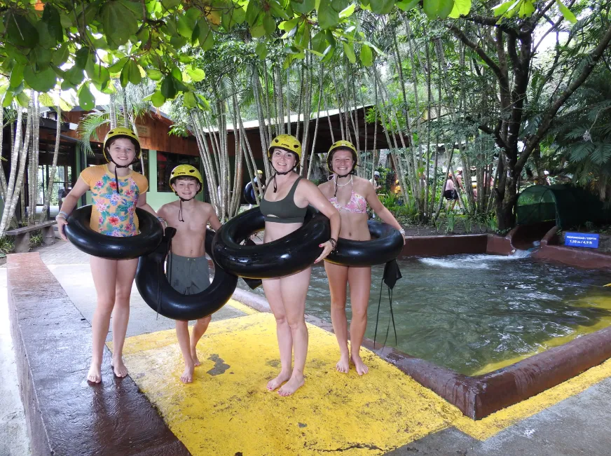 A group of people in swimwear pose together smiling in front of a colorful outdoor attraction.