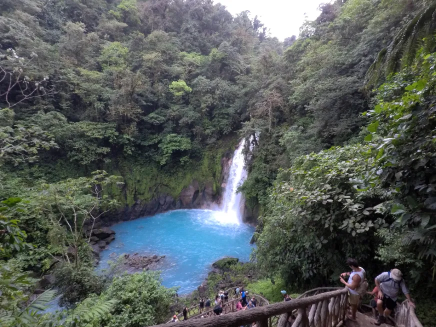 A panoramic view of the vivid turquoise Rio Celeste winding through dense green rainforest.